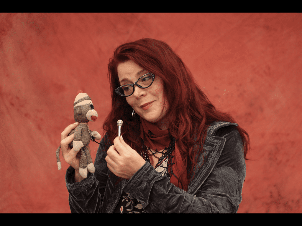 Carolyn Wonderland with stuffed monkey and microphone